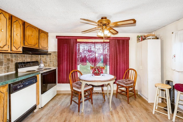 dining area with a textured ceiling, light wood-style flooring, and a ceiling fan