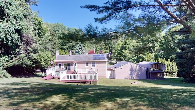 back of house with a lawn, solar panels, and a wooden deck