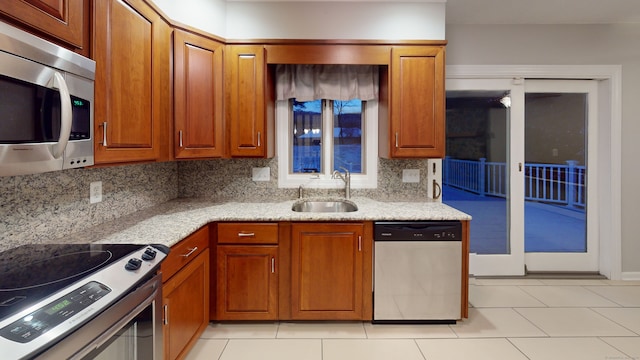 kitchen featuring decorative backsplash, appliances with stainless steel finishes, light stone countertops, sink, and light tile patterned floors