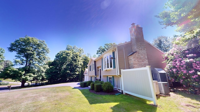 view of side of property with cooling unit and a lawn