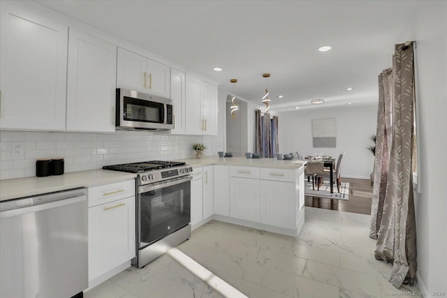 kitchen with kitchen peninsula, stainless steel appliances, white cabinets, and pendant lighting