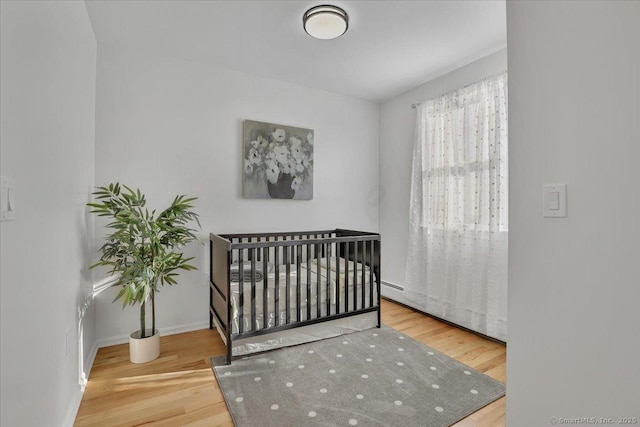 bedroom featuring a nursery area and hardwood / wood-style floors