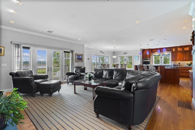 living room featuring crown molding, plenty of natural light, light hardwood / wood-style floors, and french doors