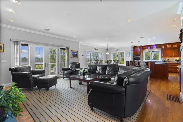 living area featuring light wood-style floors, visible vents, crown molding, and french doors