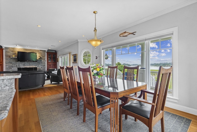 dining space with a fireplace, recessed lighting, ornamental molding, wood finished floors, and baseboards