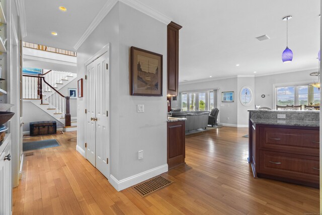 corridor featuring light wood-type flooring and ornamental molding