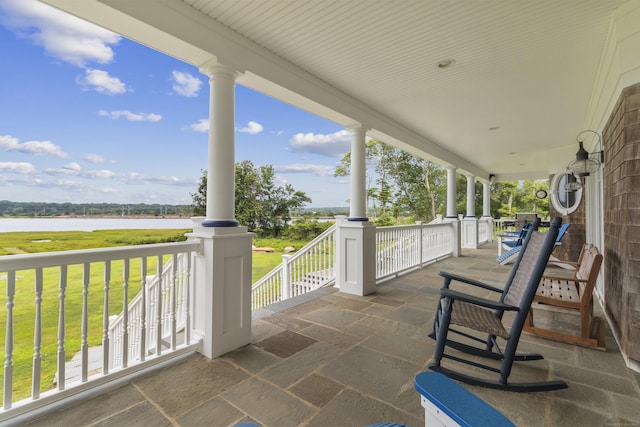 view of patio / terrace with a water view and a porch