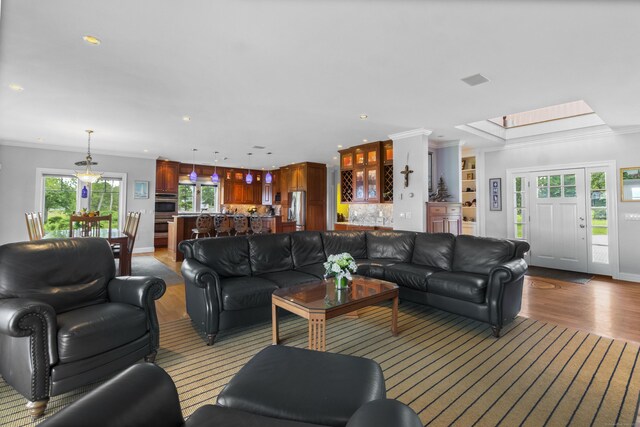 living area with baseboards, recessed lighting, light wood-type flooring, and crown molding