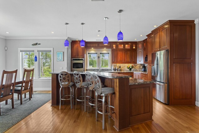 kitchen featuring a center island, dark stone counters, hanging light fixtures, decorative backsplash, and stainless steel appliances