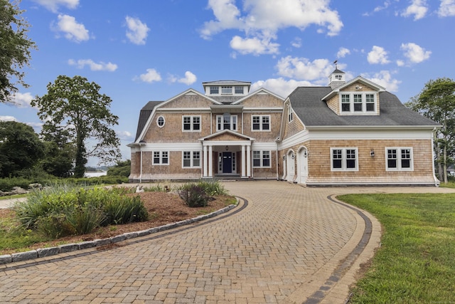 shingle-style home with decorative driveway and a front yard