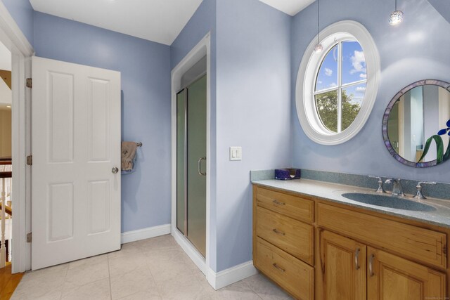 bathroom featuring tile patterned floors, a shower stall, baseboards, and vanity