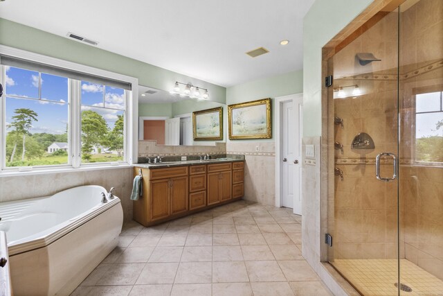 bathroom featuring plus walk in shower, vanity, tile walls, and tile patterned flooring