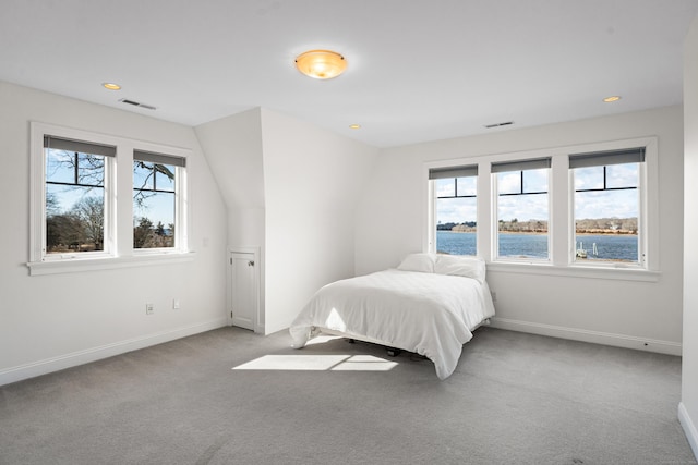 bedroom with carpet, visible vents, a water view, and baseboards