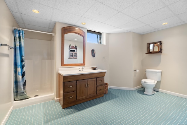 bathroom featuring baseboards, toilet, vanity, a paneled ceiling, and a shower stall