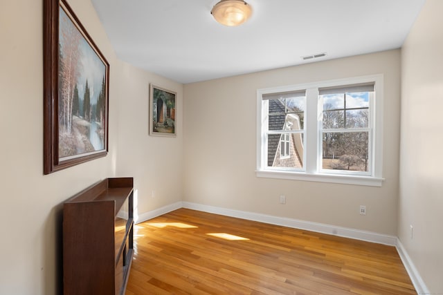 empty room with light wood-type flooring, baseboards, and visible vents