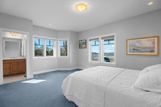 bedroom featuring recessed lighting, light colored carpet, ensuite bathroom, a sink, and baseboards