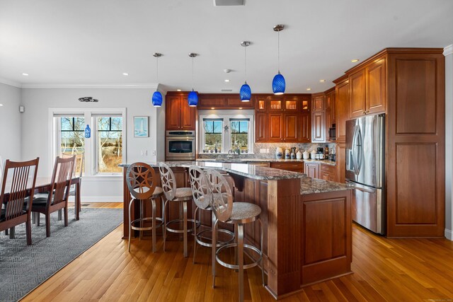 kitchen with tasteful backsplash, appliances with stainless steel finishes, crown molding, and wood finished floors