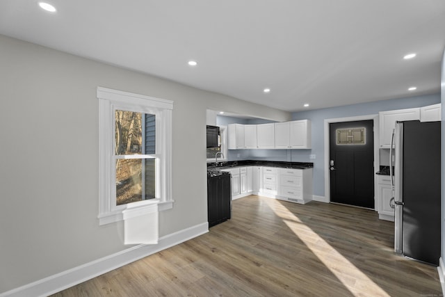 kitchen with wood-type flooring, white cabinetry, sink, and stainless steel refrigerator