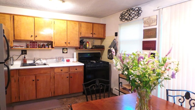 kitchen with stainless steel fridge, black gas range oven, a textured ceiling, and sink