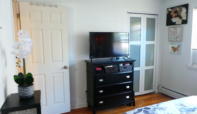 bedroom with baseboard heating and hardwood / wood-style flooring