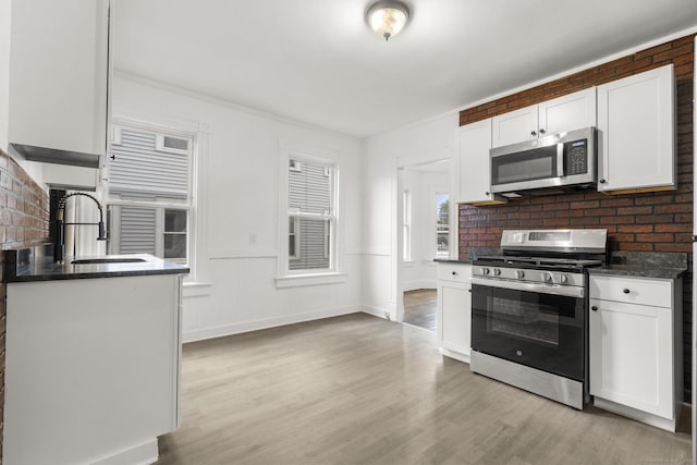 kitchen featuring white cabinets, light wood-type flooring, sink, and appliances with stainless steel finishes