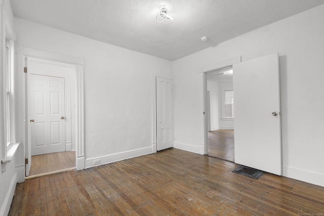 unfurnished bedroom with a textured ceiling and dark hardwood / wood-style floors