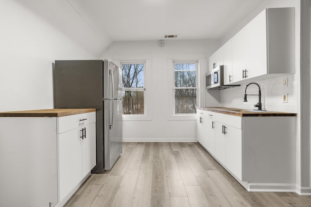 kitchen featuring appliances with stainless steel finishes, tasteful backsplash, sink, white cabinets, and light hardwood / wood-style floors