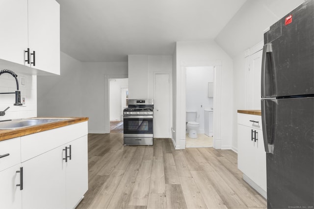 kitchen featuring refrigerator, white cabinetry, gas stove, and sink