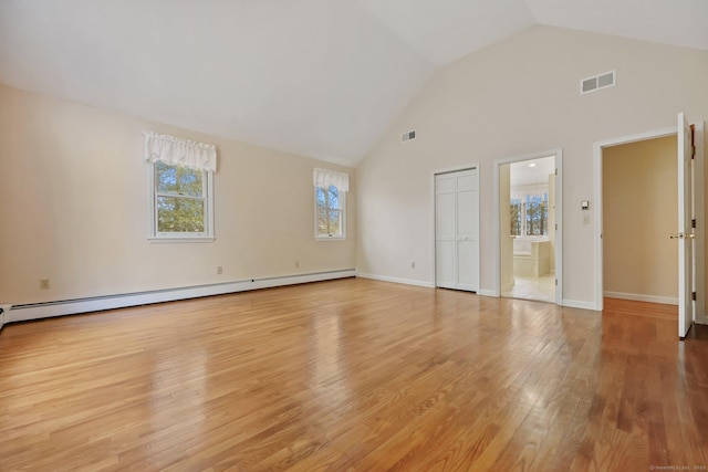 unfurnished room featuring a baseboard radiator, vaulted ceiling, and light wood-type flooring