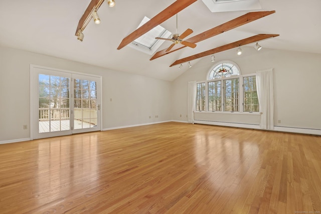 unfurnished living room with light hardwood / wood-style flooring, track lighting, ceiling fan, vaulted ceiling with skylight, and a baseboard heating unit