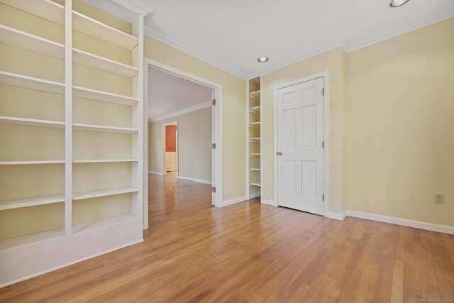 unfurnished room with crown molding, built in features, and hardwood / wood-style flooring