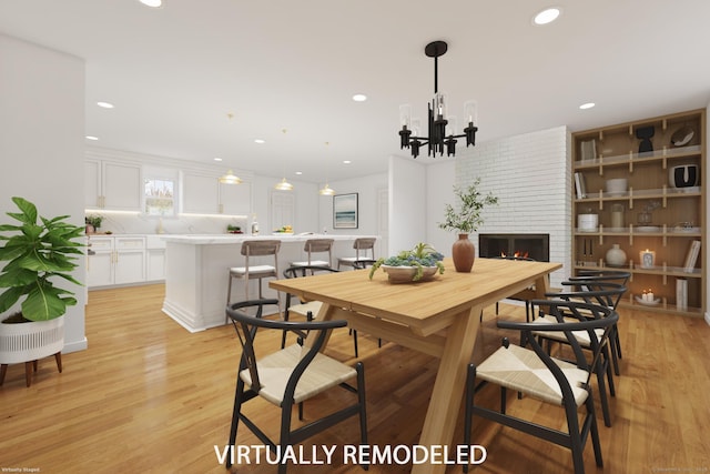 dining space with a fireplace, a chandelier, and light wood-type flooring