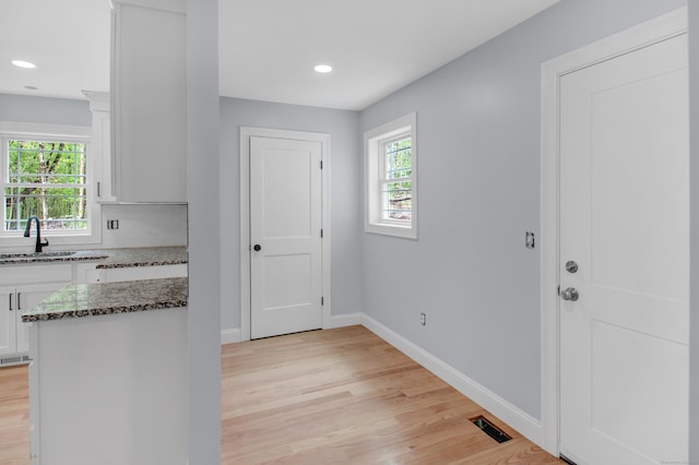 629 Hartford Rd, Salem, CT 06420 - kitchen featuring a sink, white cabinetry, dark stone countertops, light wood-style floors, and baseboards