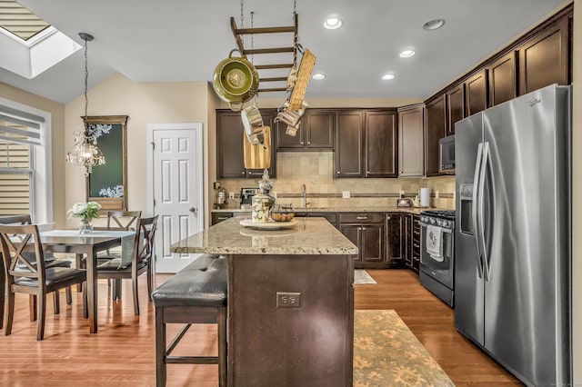 kitchen featuring dark brown cabinetry, a center island, hanging light fixtures, and appliances with stainless steel finishes