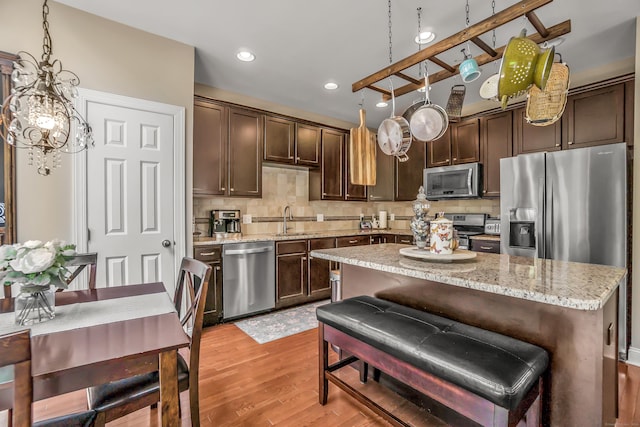 kitchen with sink, tasteful backsplash, pendant lighting, a kitchen island, and appliances with stainless steel finishes