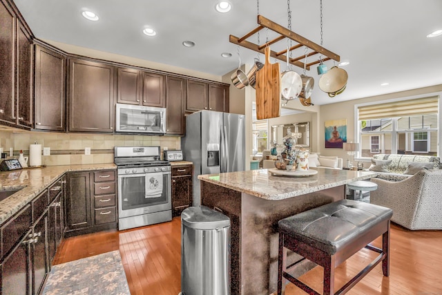 kitchen with a kitchen bar, backsplash, stainless steel appliances, and light hardwood / wood-style floors