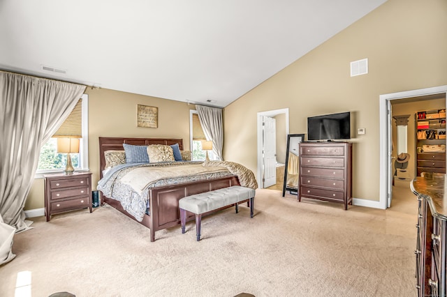 bedroom featuring light carpet, a spacious closet, and vaulted ceiling