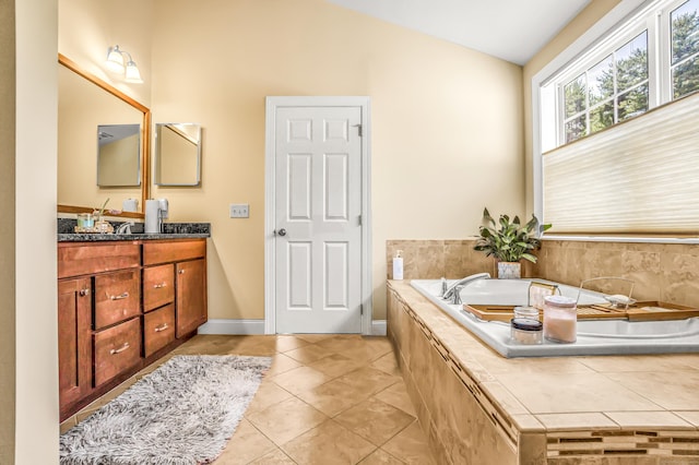 bathroom featuring tile patterned flooring, vanity, tiled bath, and vaulted ceiling