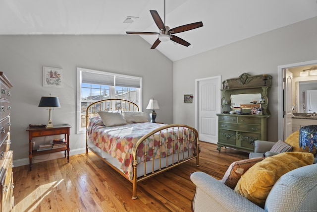 bedroom featuring connected bathroom, ceiling fan, light hardwood / wood-style floors, and vaulted ceiling