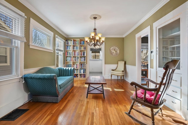 sitting room with wood-type flooring, a chandelier, and ornamental molding