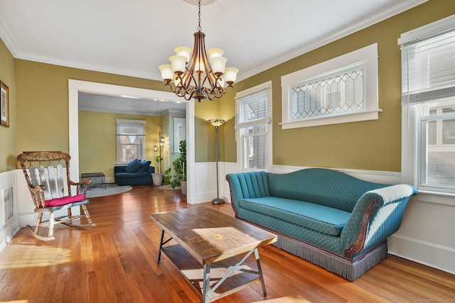 sitting room featuring wood-type flooring, crown molding, and a notable chandelier