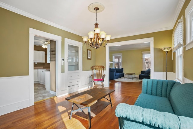 living room with dark hardwood / wood-style floors, ornamental molding, and ceiling fan with notable chandelier