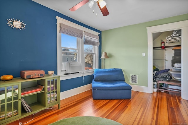 sitting room with ceiling fan and wood-type flooring