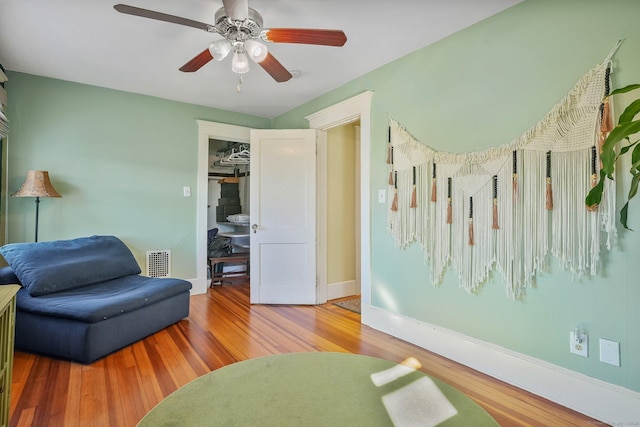 living area featuring hardwood / wood-style floors and ceiling fan