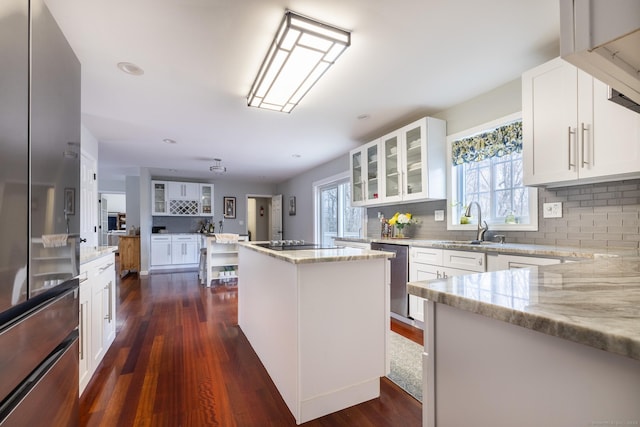 kitchen featuring appliances with stainless steel finishes, tasteful backsplash, light stone counters, white cabinets, and a center island