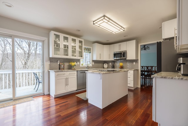 kitchen featuring light stone countertops, dark hardwood / wood-style flooring, stainless steel appliances, a kitchen island, and white cabinetry