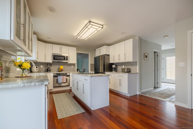 kitchen with backsplash, white cabinetry, a kitchen island, and appliances with stainless steel finishes