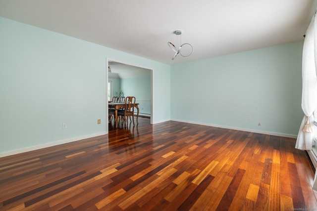 empty room with an inviting chandelier and dark wood-type flooring