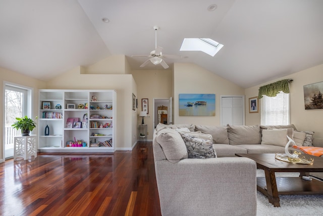 living room with ceiling fan, vaulted ceiling with skylight, a healthy amount of sunlight, and dark hardwood / wood-style floors