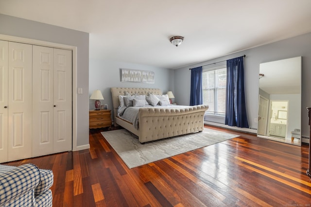 bedroom featuring dark hardwood / wood-style flooring, baseboard heating, and a closet